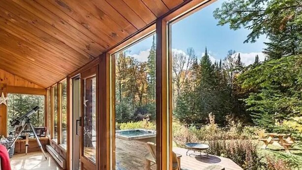 A wooden cabin with large windows, a telescope, and a deck with outdoor furniture. - The Beaver Lodge by Escapades Tremblant (Lac-Superieur)