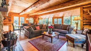 A log cabin interior with a wooden ceiling, a sofa, a coffee table, and a dining area. - The Beaver Lodge by Escapades Tremblant (Lac-Superieur)