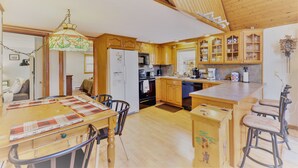 A kitchen with wooden cabinets, a dining table with chairs, a refrigerator, and a coffee maker. - ARROWHEAD LAKE - Ski Chalet- Gameroom, Firepit - Lake View, Walk to Beach/Island (Pocono Lake)