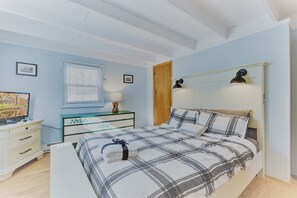 Un dormitorio con cama, mesitas de noche, lámpara y ventana con persianas.