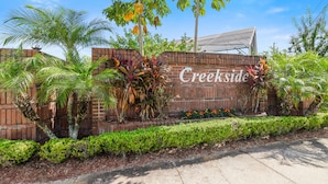 A brick wall with the name "Creekside" and lush greenery including palm trees and tropical plants. - Private Heated Pool, Game Room, 8 mi to Disney, Walk to #GKTW! (Kissimmee)