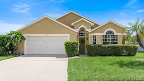A single-story house with a garage, a front door, and a small porch. - Private Heated Pool, Game Room, 8 mi to Disney, Walk to #GKTW! (Kissimmee)