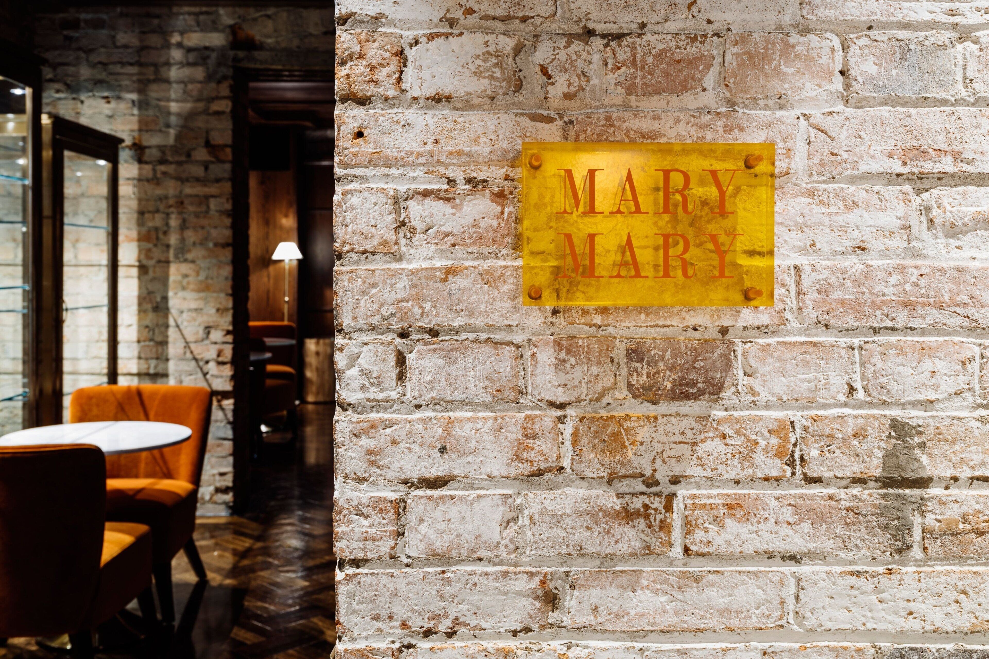 Un mur de briques sur lequel est apposée une enseigne jaune avec l’inscription « MARY MARY ».