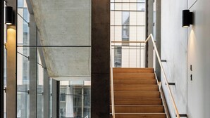 Een modern interieur met een houten trap, grote ramen en een betonnen muur.