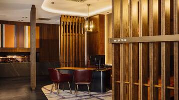 Una moderna zona de recepción con un mostrador de madera, dos sillones de cuero y un cartel que indica la recepción.