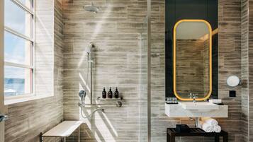 Une salle de bain moderne avec une douche, un meuble-lavabo avec un miroir et un banc.