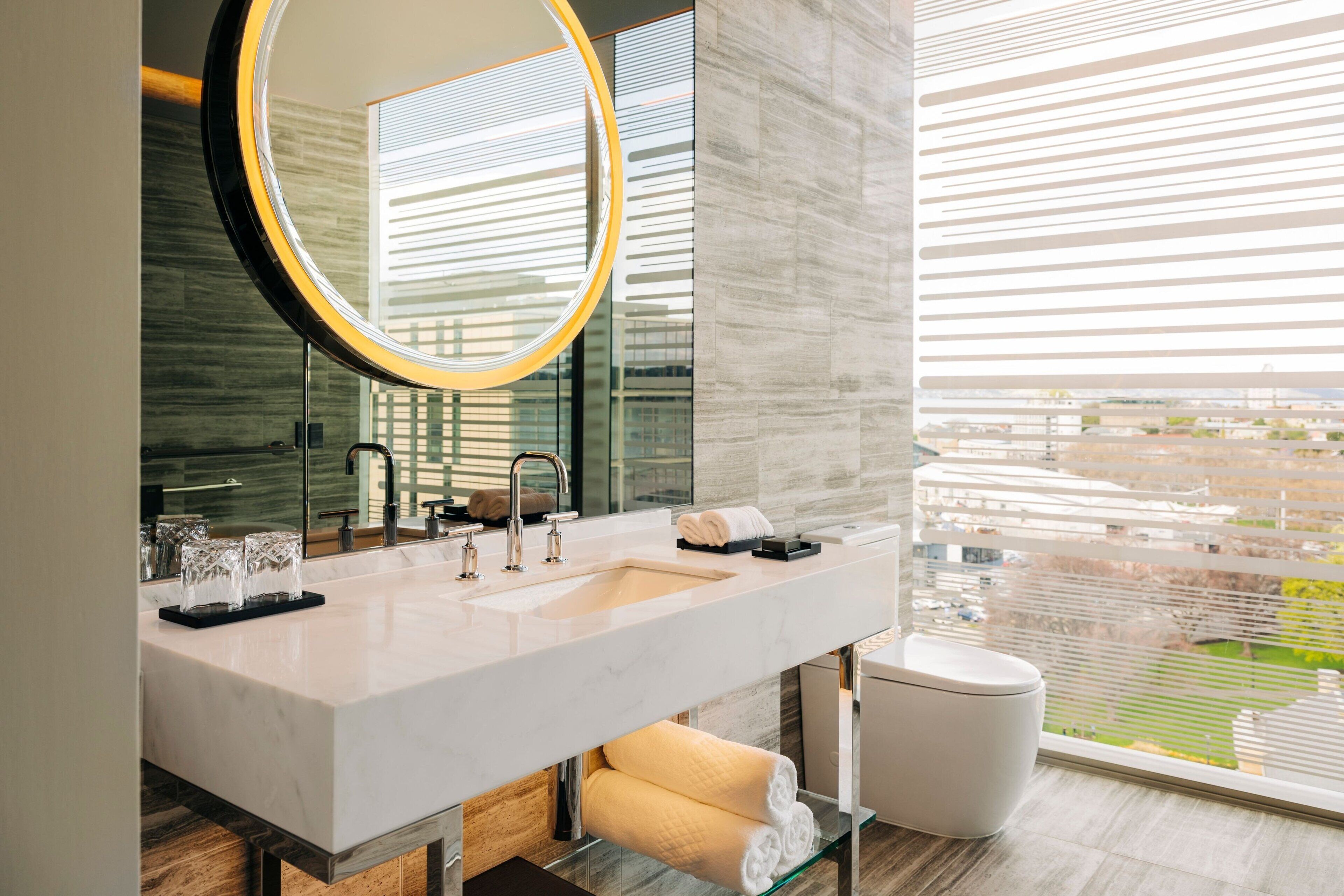 Un baño moderno con un espejo grande, dos lavamanos y un inodoro.