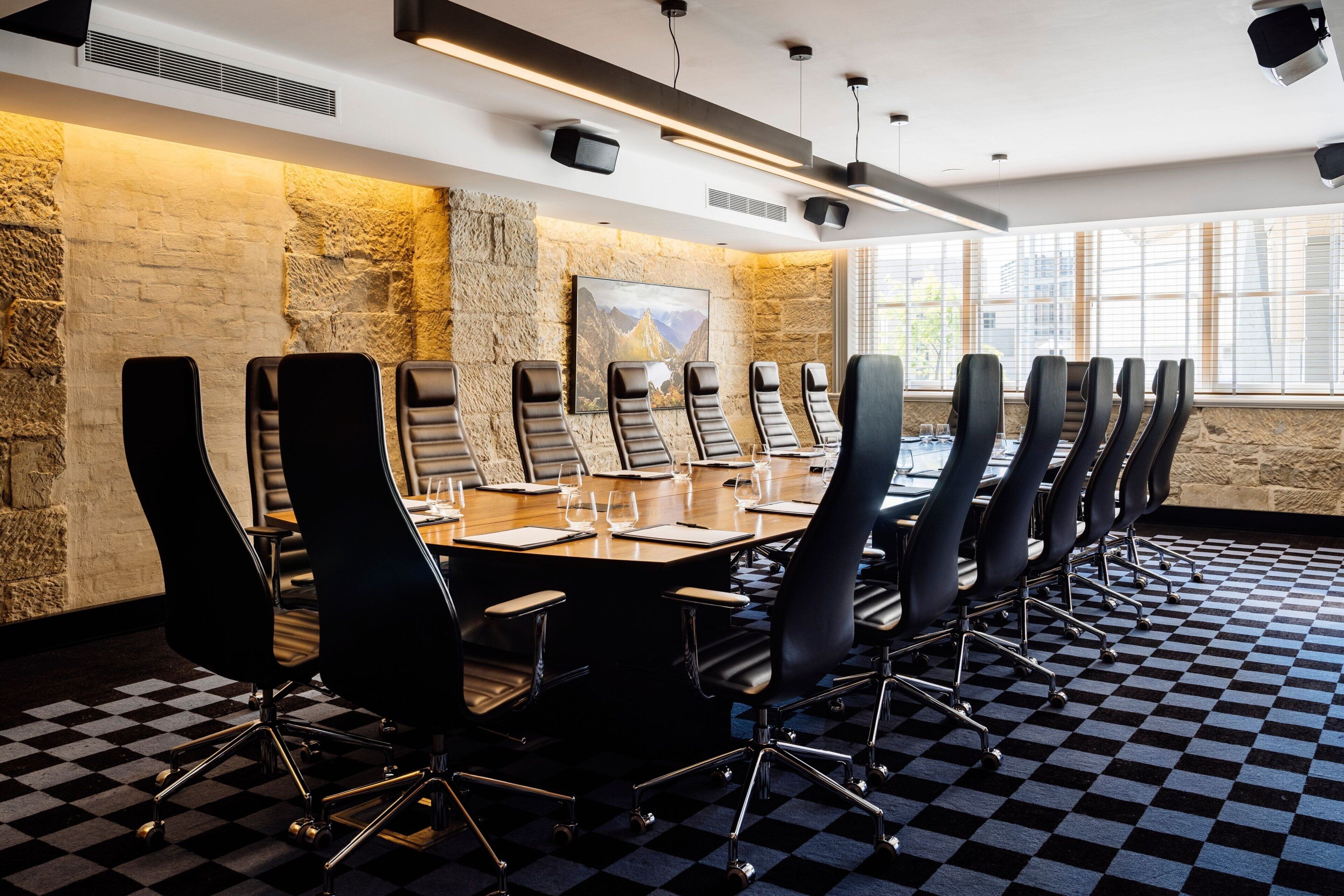 A conference room with a long table, black chairs, and a checkered floor.