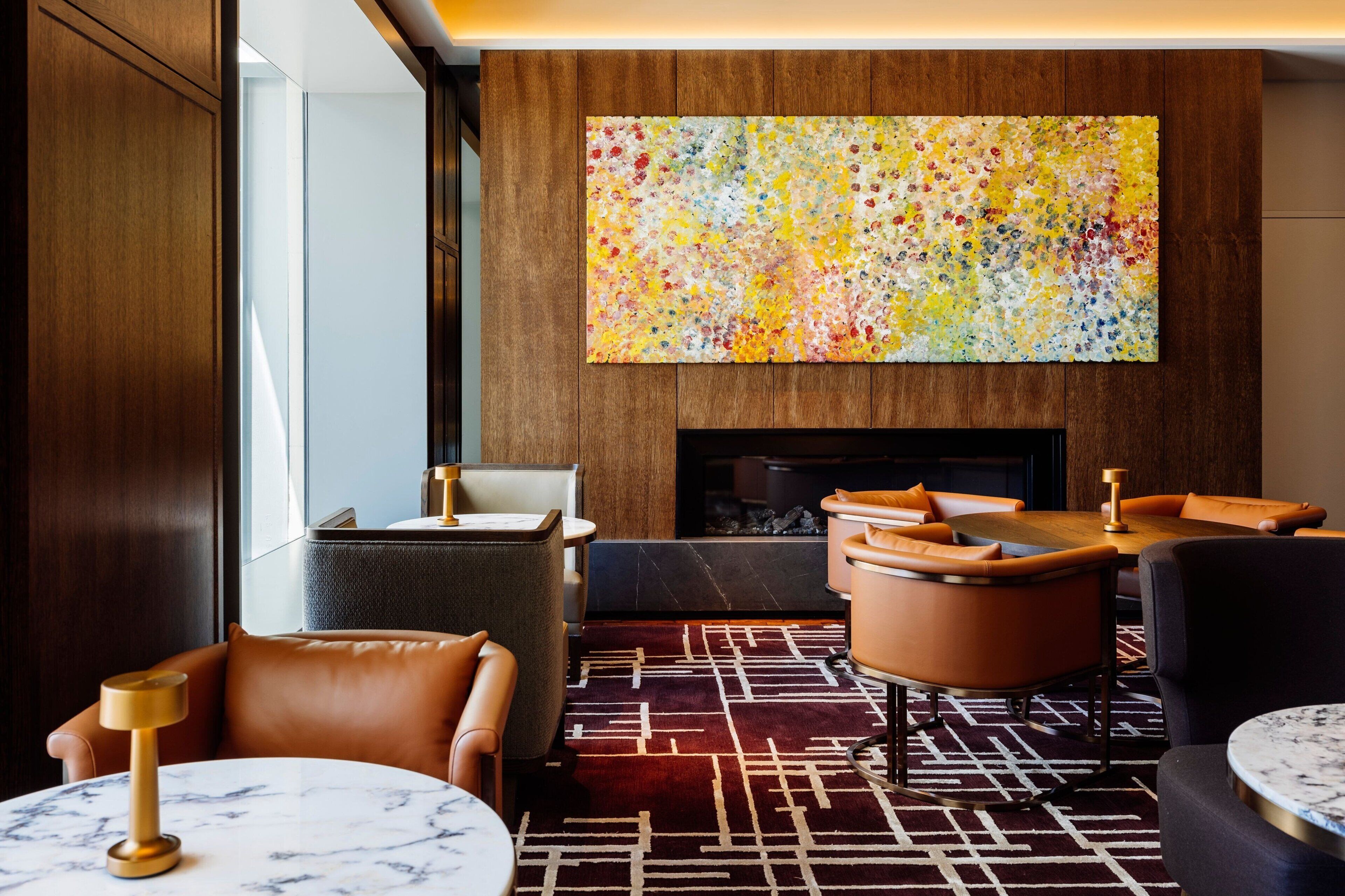 A modern lounge with leather seating, a fireplace, and a colorful abstract painting.