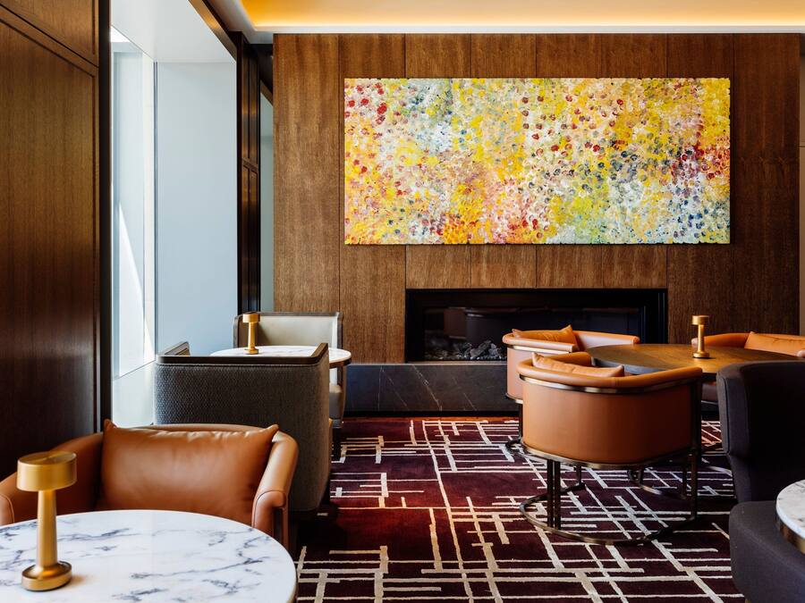 A modern lounge with leather seating, a fireplace, and a colorful abstract painting.