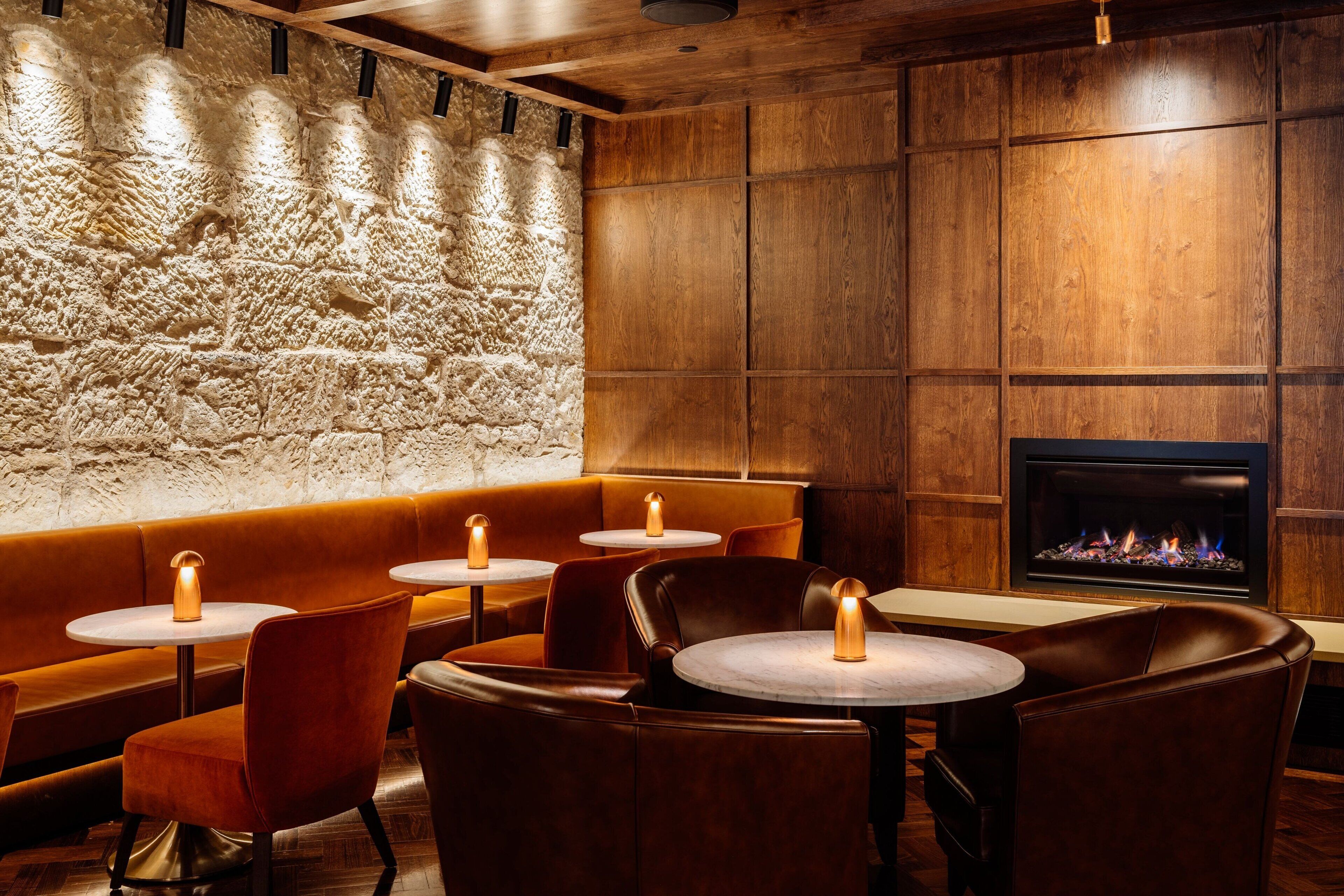 A cozy restaurant with wooden walls, stone accents, and a fireplace.