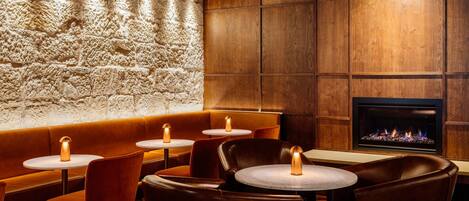 A cozy restaurant with wooden walls, stone accents, and a fireplace.