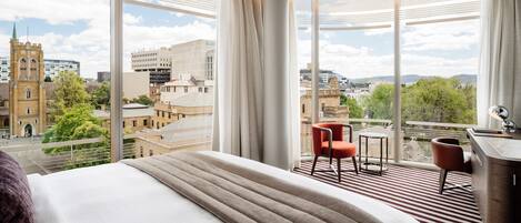 Habitación de hotel con una cama grande, un escritorio y una silla, con vista a la ciudad y una torre.