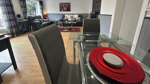 A modern living room with a glass dining table, a sofa, and a coffee table. - Solway Cottage (Annan)