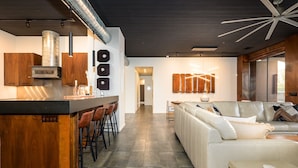 Une cuisine moderne dotée d’un îlot central, de meubles en bois et d’un four encastré. On y trouve également un coin salon avec un canapé blanc et une table à manger.
