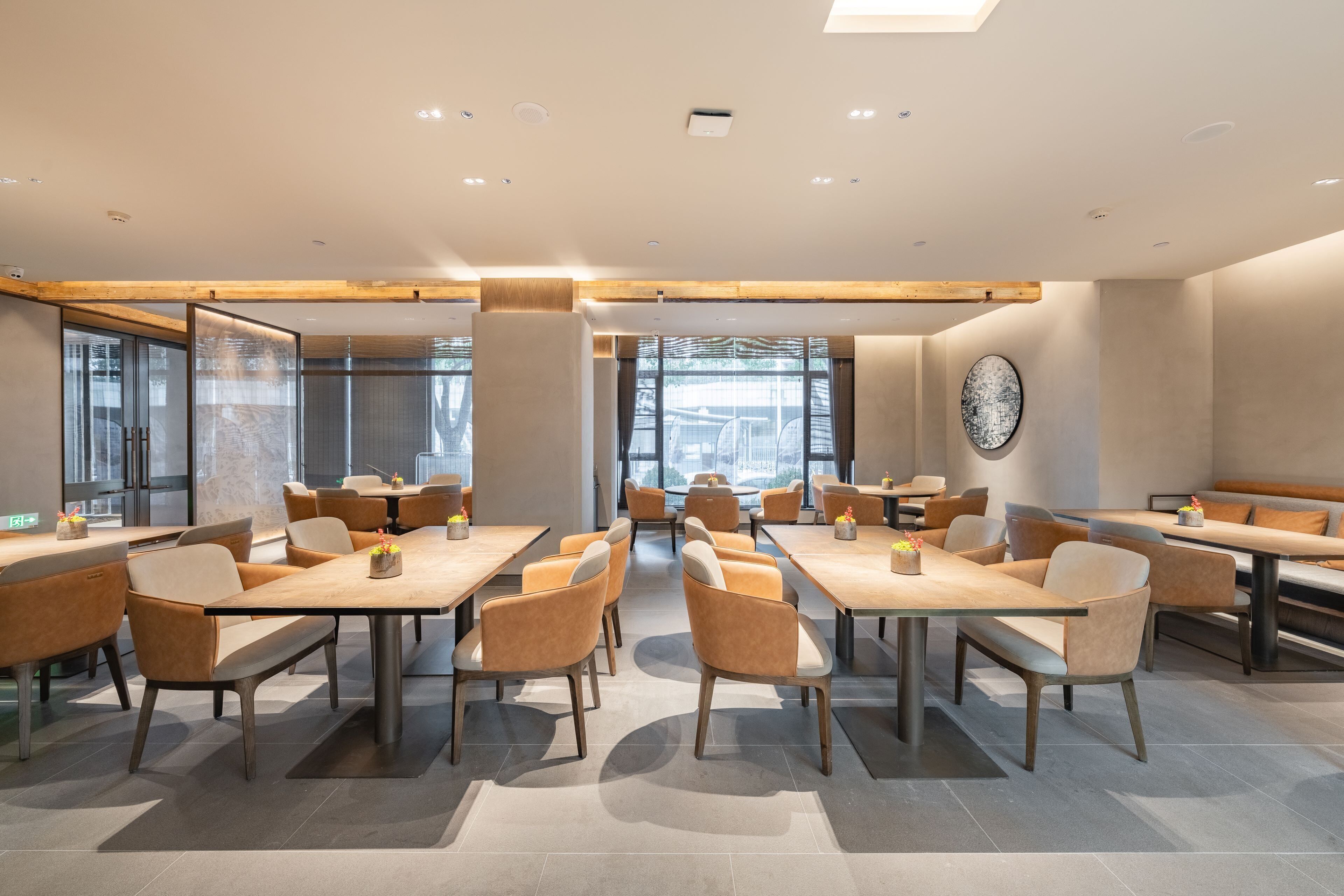 A modern dining area with multiple tables and chairs, large windows, and a minimalist design.