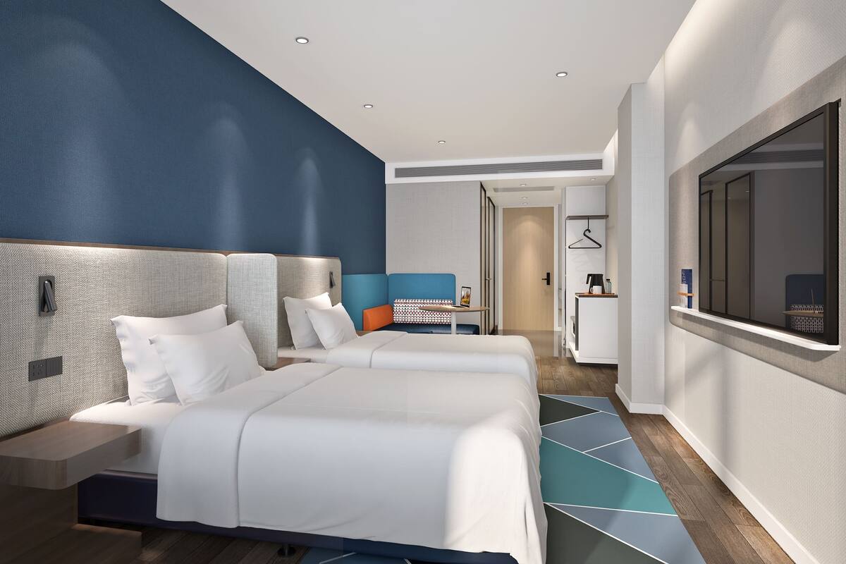 Una camera d'albergo moderna con un letto grande, una scrivania e una televisione.