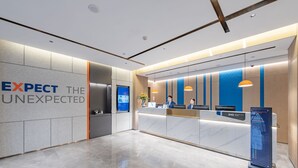 A modern hotel reception area with a marble floor, a reception desk, and a wall with the text "EXPECT THE UNEXPECTED". - Holiday Inn Express Shanghai Expo Centre by IHG (Shanghai)