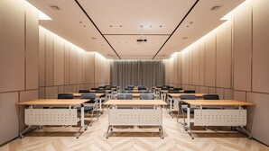 A conference room with a large screen at the front, rows of tables and chairs, and a herringbone-patterned floor. - Holiday Inn Express Shanghai Expo Centre by IHG (Shanghai)