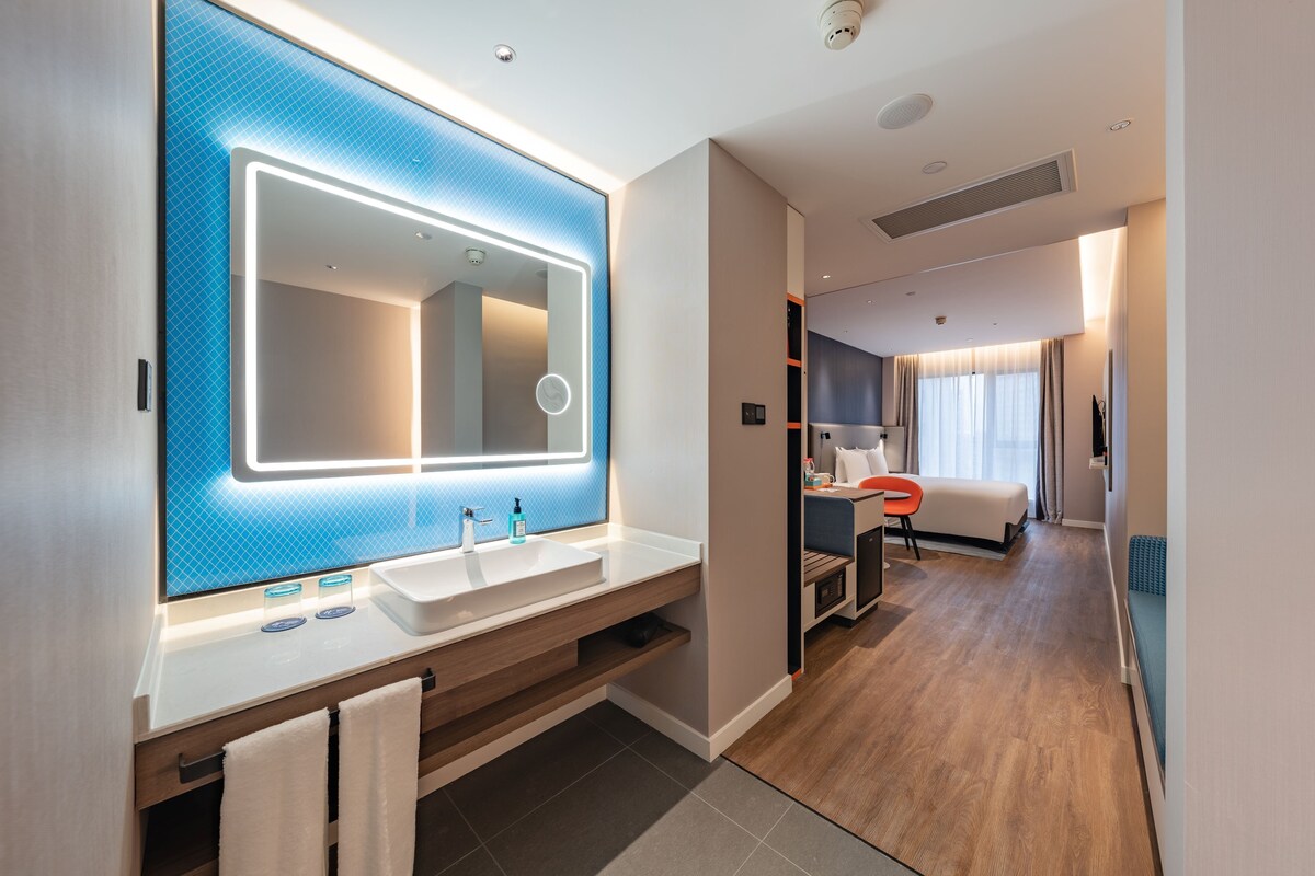 Un baño moderno con un espejo grande, dos lavamanos y un mueble de tocador.