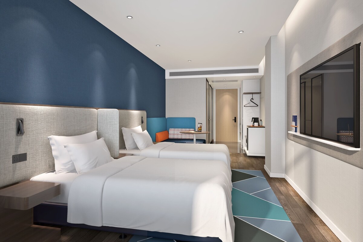 Una habitación de hotel moderna con una cama grande, un escritorio y un televisor.