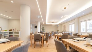 Un comedor moderno con mesas de madera y sillas grises, con iluminación empotrada y un diseño limpio y minimalista.