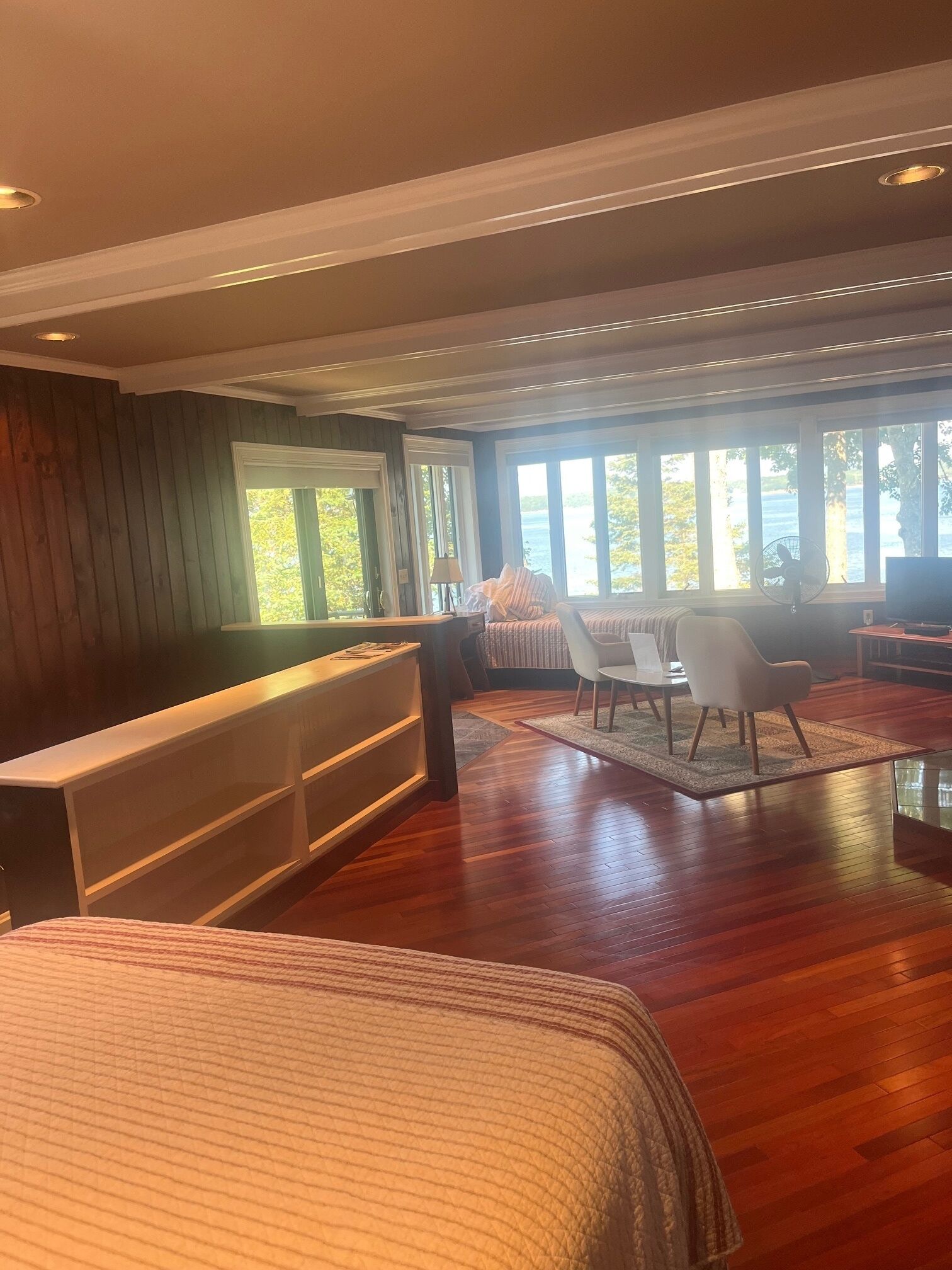 Habitación amplia con una cama grande, un escritorio y una silla. Varias ventanas ofrecen vistas al exterior.
