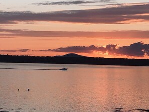 A calm lake at sunset with a boat and buoys in the foreground.