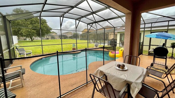 Un espace extérieur abrité comprenant une piscine, des sièges et un barbecue.