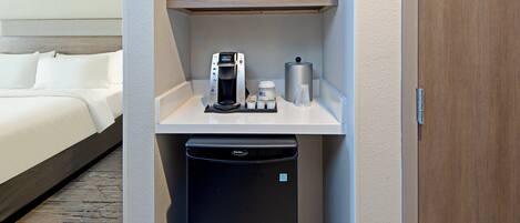 A compact kitchenette with a microwave, coffee maker, and a trash bin.