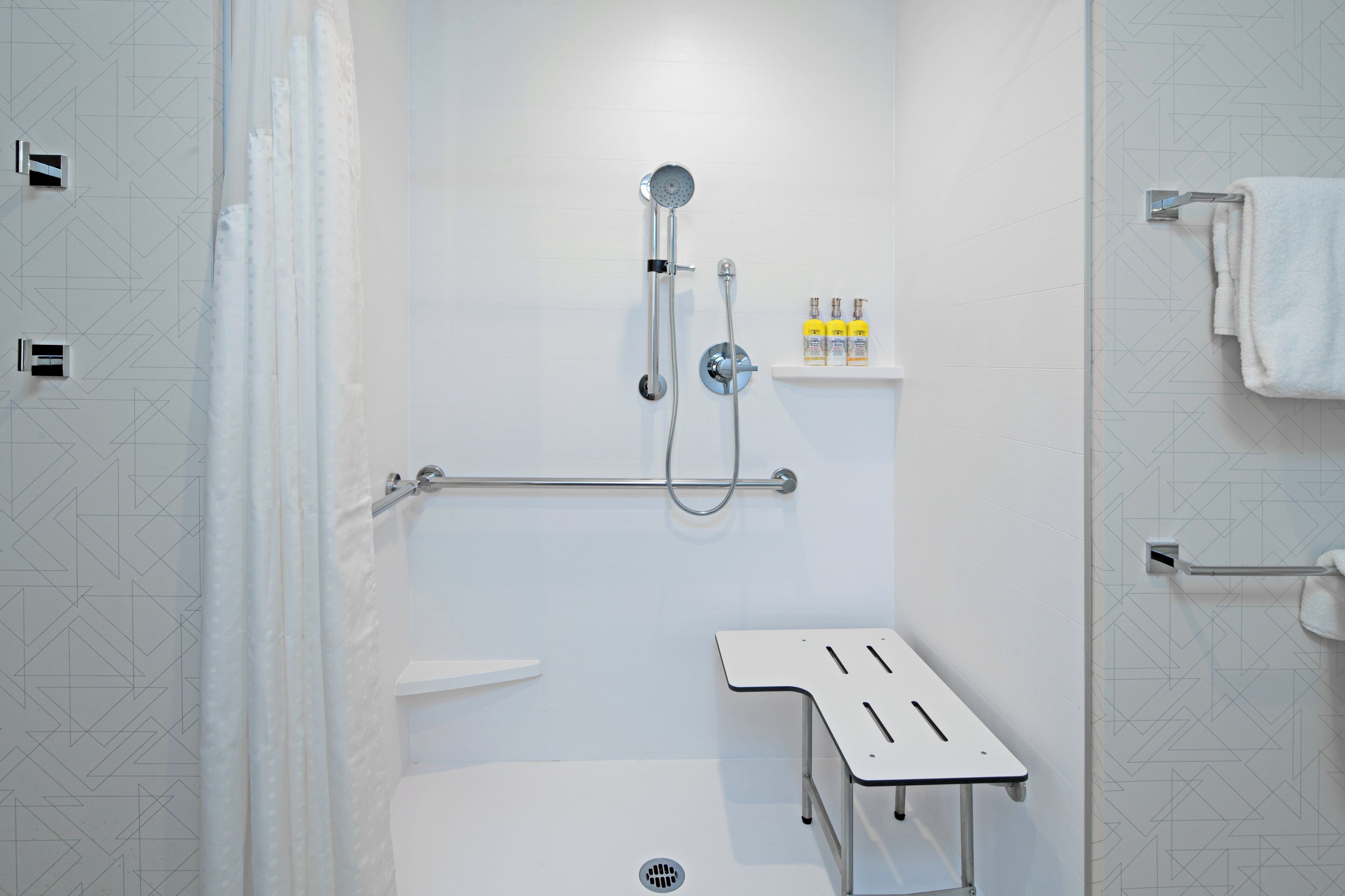 Une salle de bain moderne équipée d’une douche, de toilettes et d’une petite étagère où sont rangés les articles de toilette.