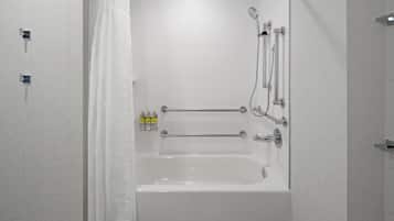 A white bathtub with a showerhead, a towel rack, and a bottle of shampoo.