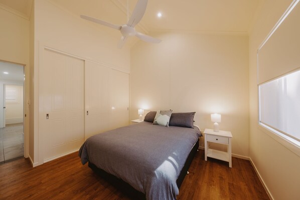 A bedroom with a bed, nightstands, a ceiling fan, and a window.