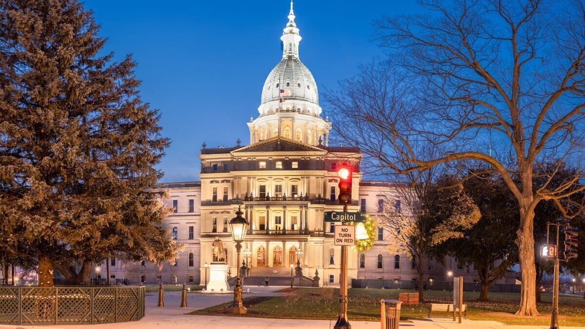 A large, historic building with a prominent dome, a well-lit entrance, and a sign indicating 'Capitol Ave.'