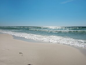 Een strand met heldere luchten en rustige golven.