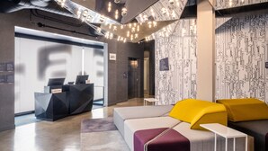 Eine moderne Lobby mit einer Rezeption, einer Sitzecke und einer Wand mit Muster.