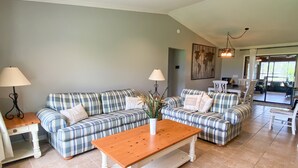 Un salon avec deux canapés à carreaux, une table basse en bois et un coin repas comprenant une table et des chaises.