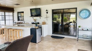 Une cuisine spacieuse avec un grand îlot central, des tabourets de bar et un ventilateur de plafond.