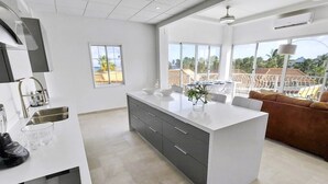 Une cuisine moderne dotée d’un grand îlot central, d’un coin repas offrant une vue agréable et d’un espace salon confortable.