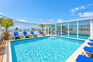 Ein Dachpool mit blauen Liegestühlen und Topfpflanzen.