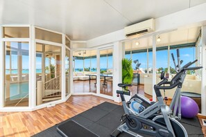 A spacious room with a view of the ocean, a ProForm exercise bike, and a purple exercise ball.