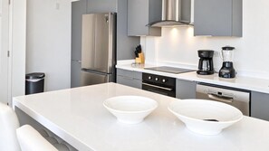 A modern kitchen with a stainless steel refrigerator, an oven, a dishwasher, and a coffee maker.