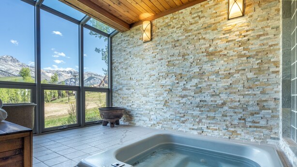 Ett spaområde med en stenmur, ett bubbelbad och utsikt över bergen.