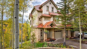 A two-story house with a red-tiled roof, a stone facade, and a front porch. - Deluxe 3 BDR/3 BA Townhome Just Steps from Skiing in Mountain Village (Mountain Village)