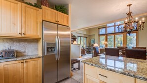 A kitchen with wooden cabinets, a stainless steel refrigerator, granite countertops, and a chandelier. - Deluxe 3 BDR/3 BA Townhome Just Steps from Skiing in Mountain Village (Mountain Village)