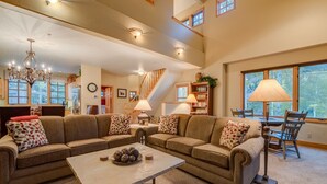 A spacious living room with a large sectional sofa, a coffee table, and a dining area with a table and chairs. - Deluxe 3 BDR/3 BA Townhome Just Steps from Skiing in Mountain Village (Mountain Village)