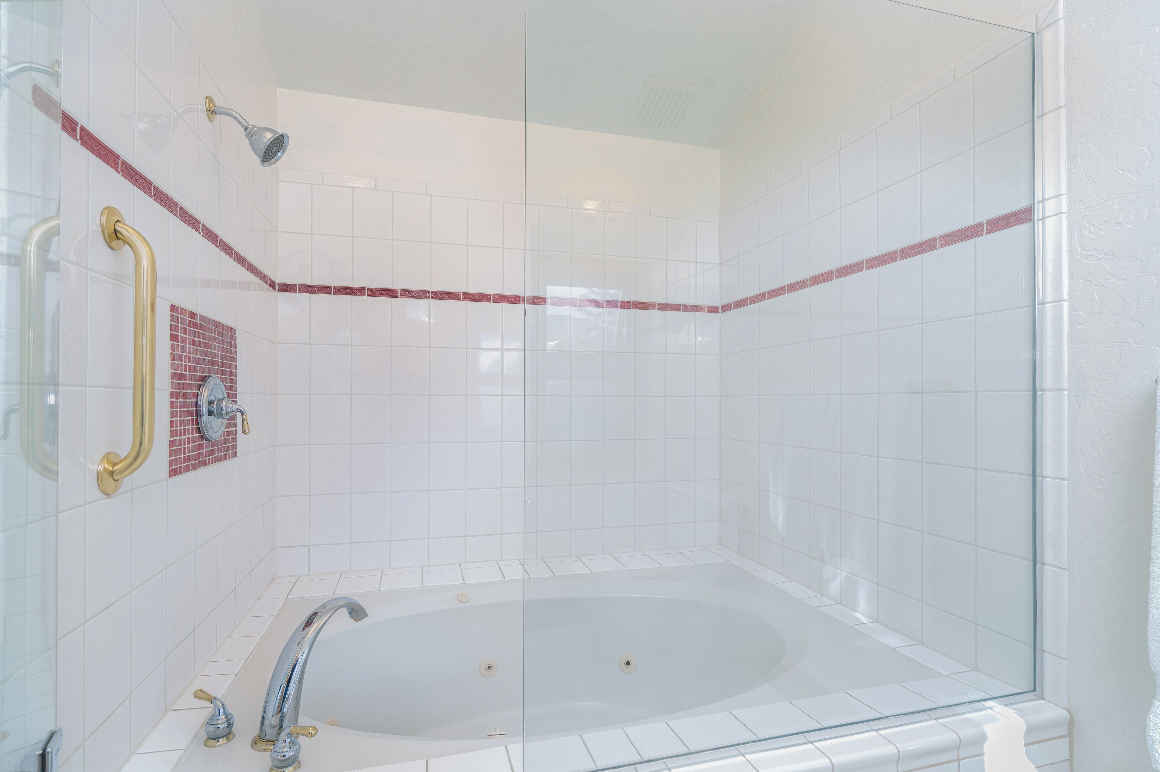 Une salle de bain moderne avec une douche à parois de verre, une baignoire sur pieds et une barre d’appui.