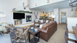 A spacious living area with a fireplace, leather sofas, a television, and a dining area with wooden chairs. - 3 BDR Mountain Village Townhome, Steps from Skiing and Dining (Mountain Village)