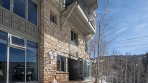 A modern building with a stone facade, large windows, and a balcony. - 3 BDR Mountain Village Townhome, Steps from Skiing and Dining (Mountain Village)