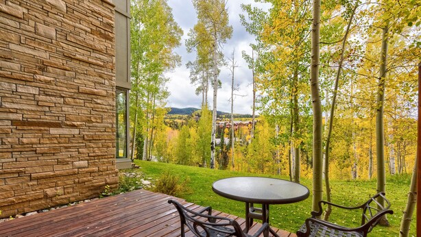 A deck with a stone wall, a table, and two chairs.